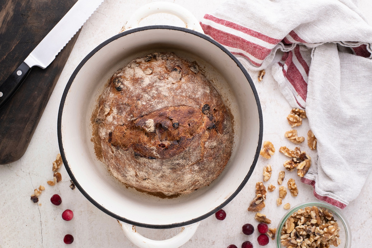 A baked loaf of bread in a white Dutch oven. 