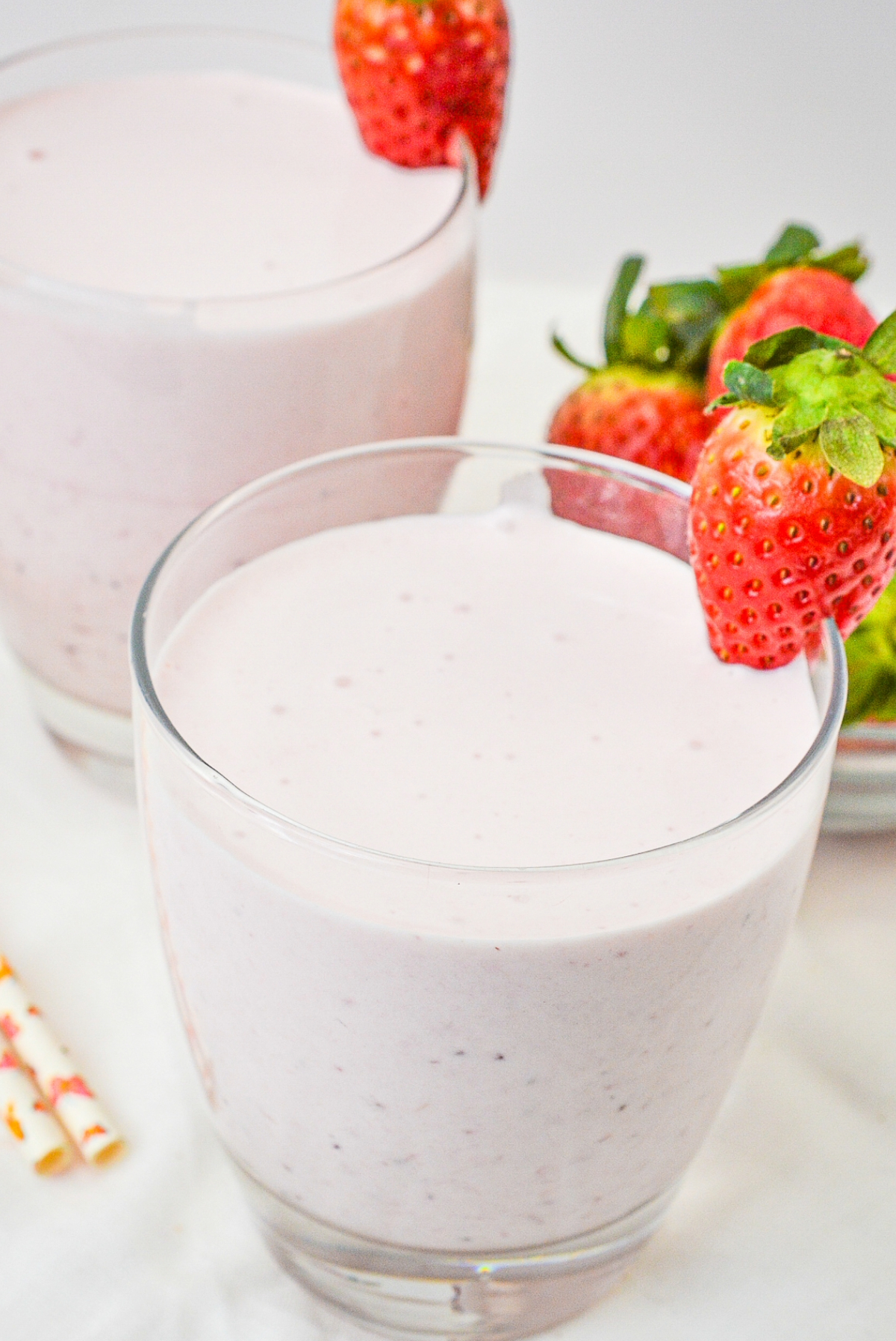 Keto strawberry banana protein smoothie in a clear glass with a fresh strawberry on top.